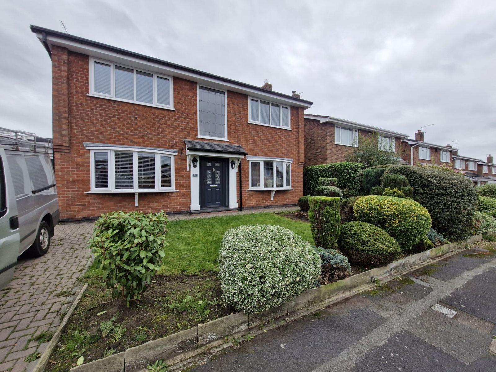 A brick house front garden with shrubs and topiary neatly shaped